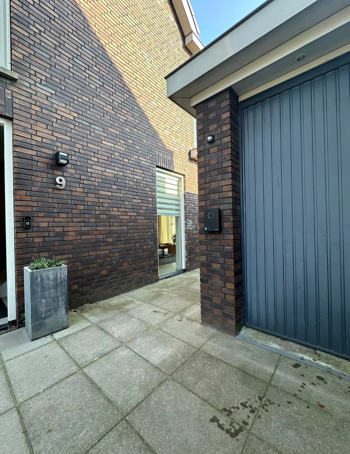 Zaptec-laadstation aan de gevel naast een garagedeur