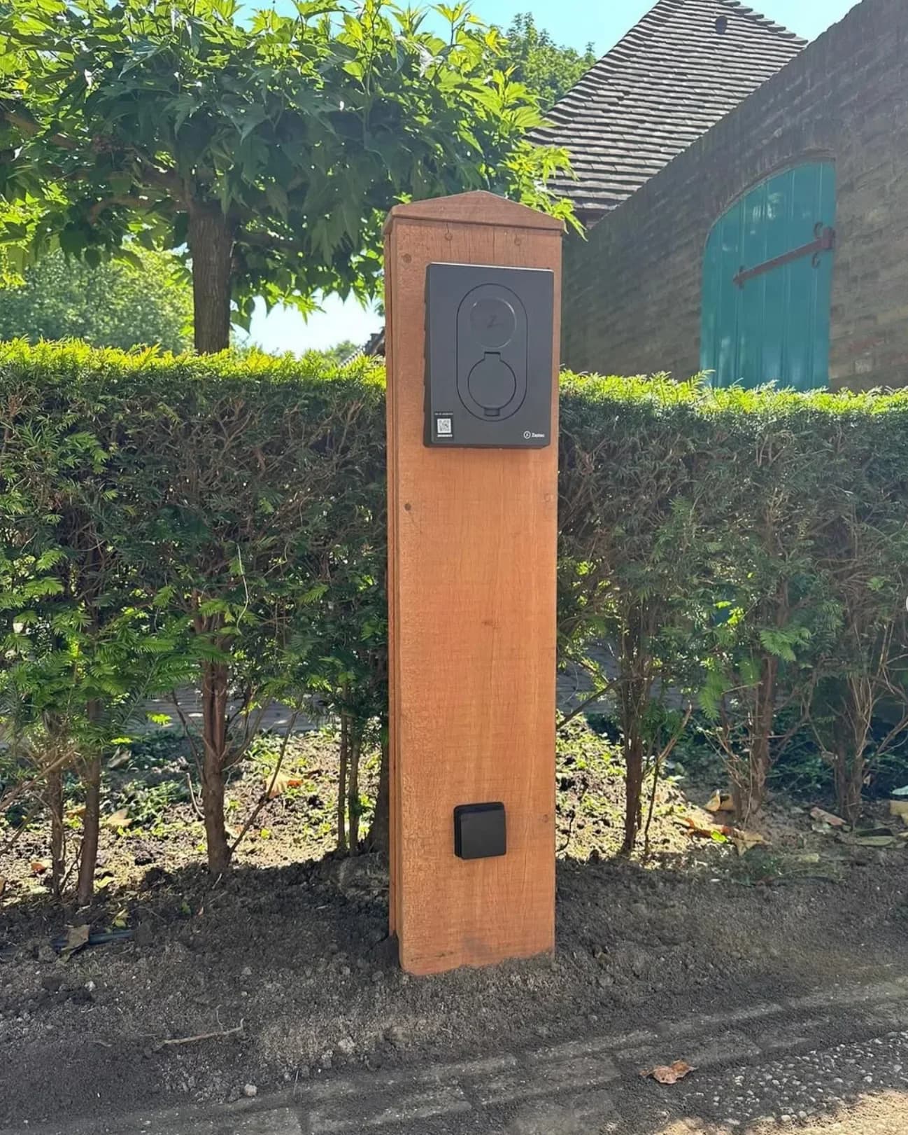 Zaptec-laadstation gemonteerd op een houten paal in een tuin
