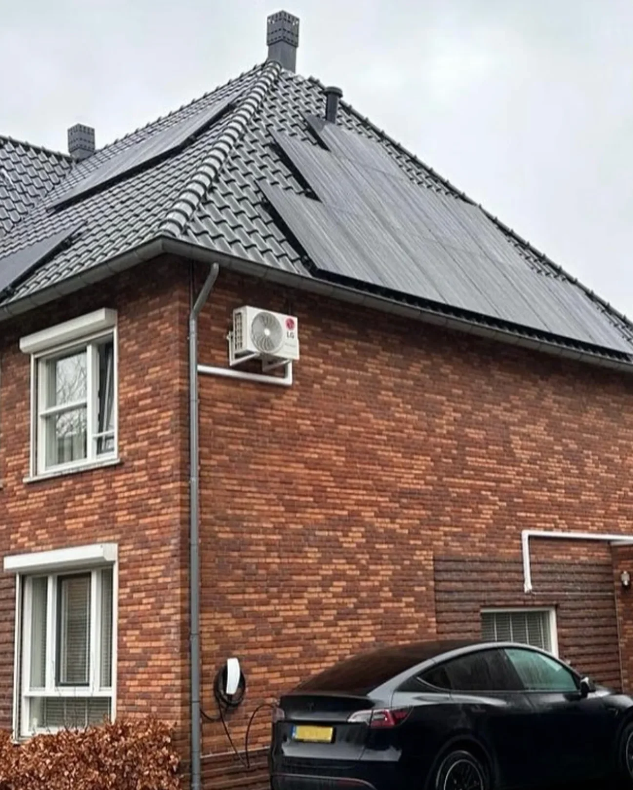 Woning met zonnepanelen op het schuine dak en een elektrische auto aan de laadpaal