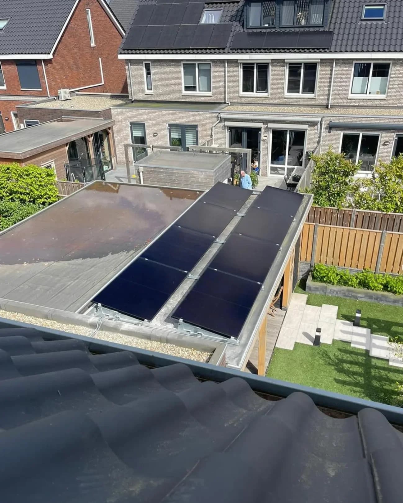 Zonnepanelen op een plat dak achter een rij woningen